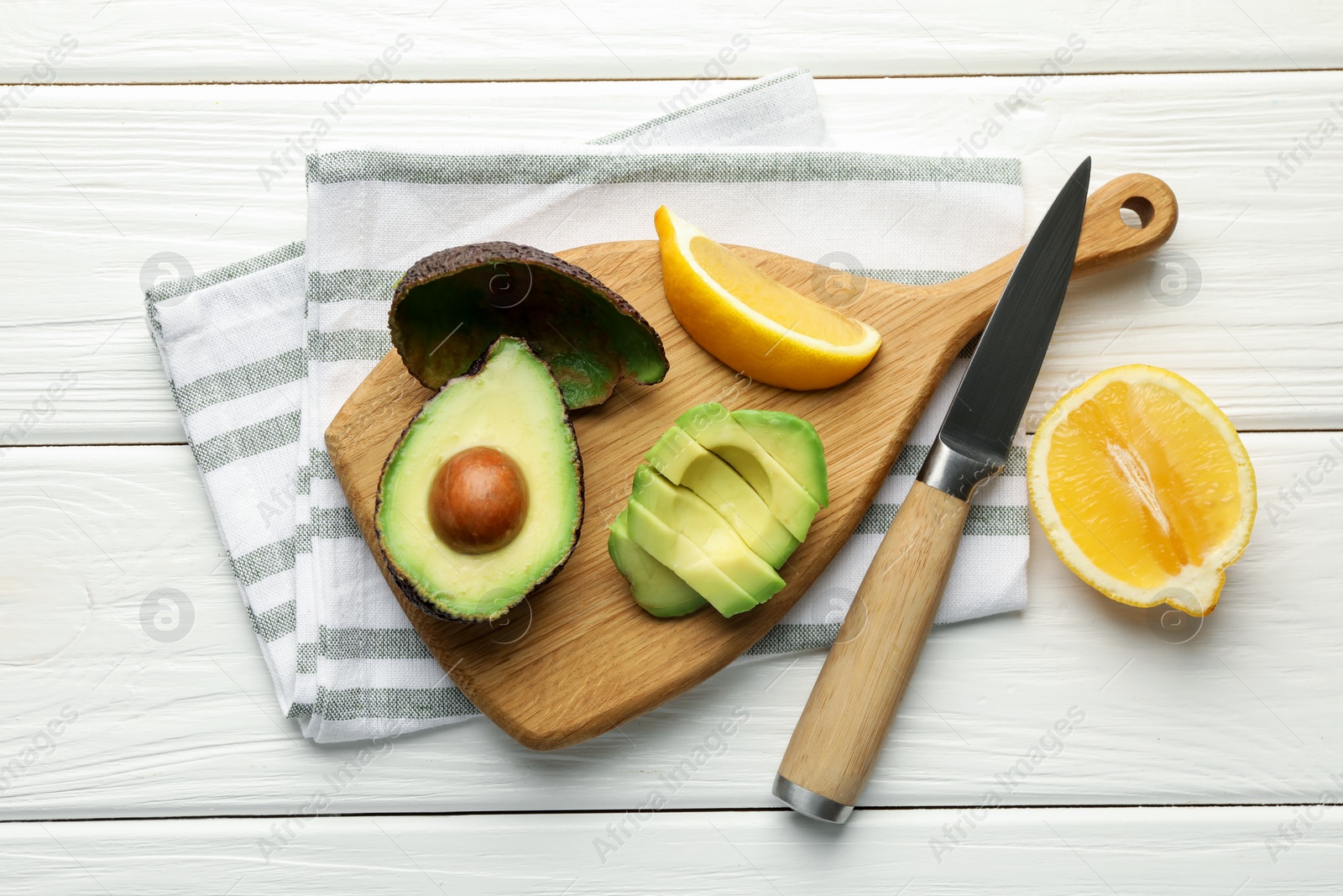 Tasty cut avocados, lemon and knife on white wooden table, flat lay Photo of Tasty cut avocados, lemon and knife on white wooden table, flat lay