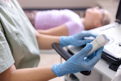 Photo of Sonographer with ultrasound machine and girl on examination bed in clinic, selective focus