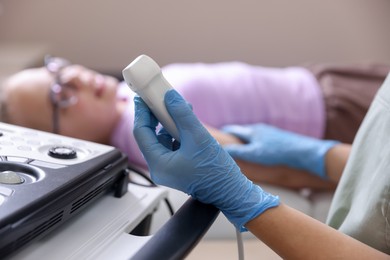 Photo of Sonographer with ultrasound machine and girl on examination bed in clinic, selective focus