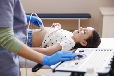 Photo of Sonographer conducting girl's abdominal ultrasound examination in clinic, closeup