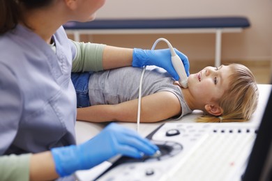 Photo of Sonographer conducting ultrasound examination of little girl's thyroid gland in clinic, closeup