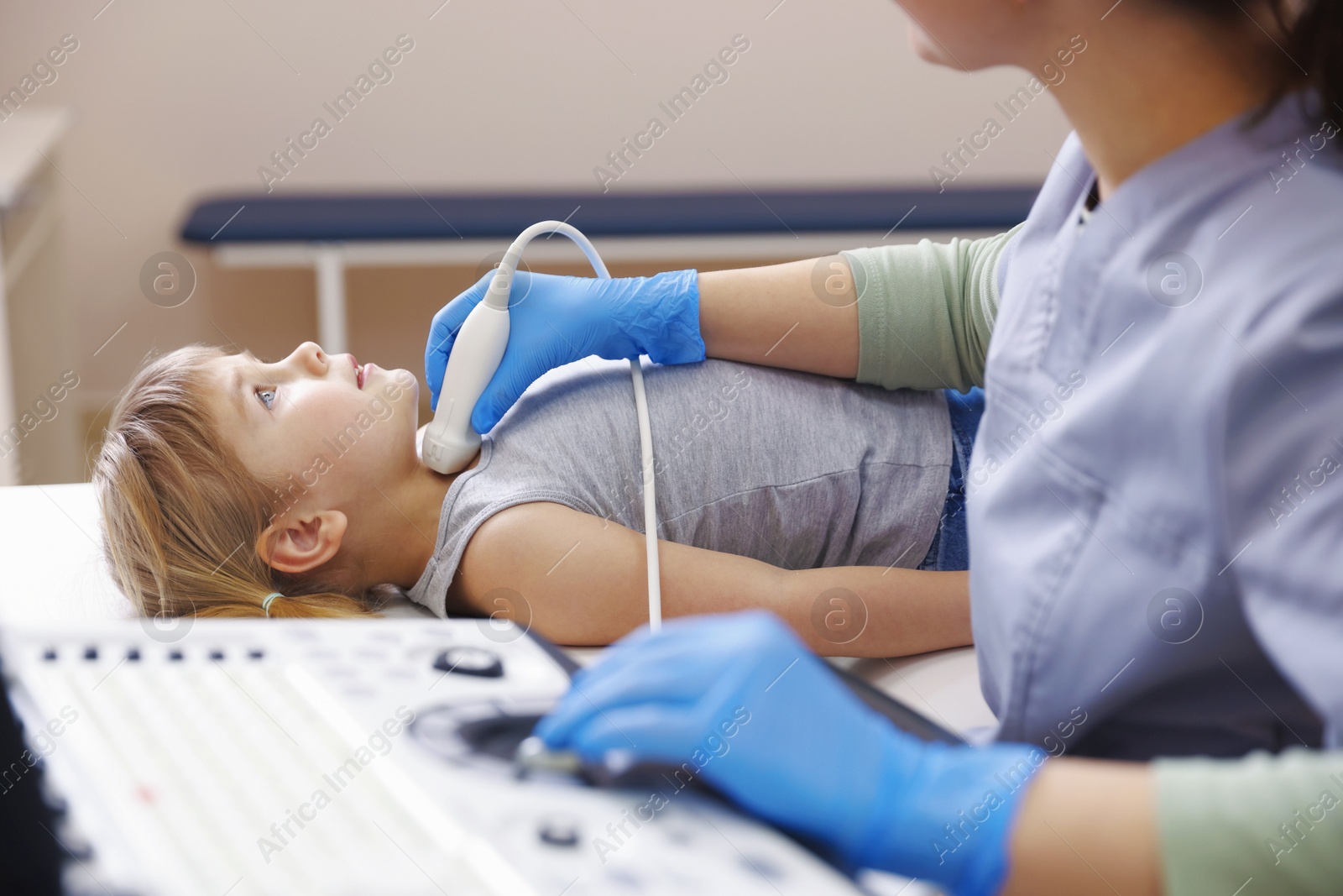 Sonographer conducting ultrasound examination of little girl's thyroid gland in clinic, closeup Photo of Sonographer conducting ultrasound examination of little girl's thyroid gland in clinic, closeup