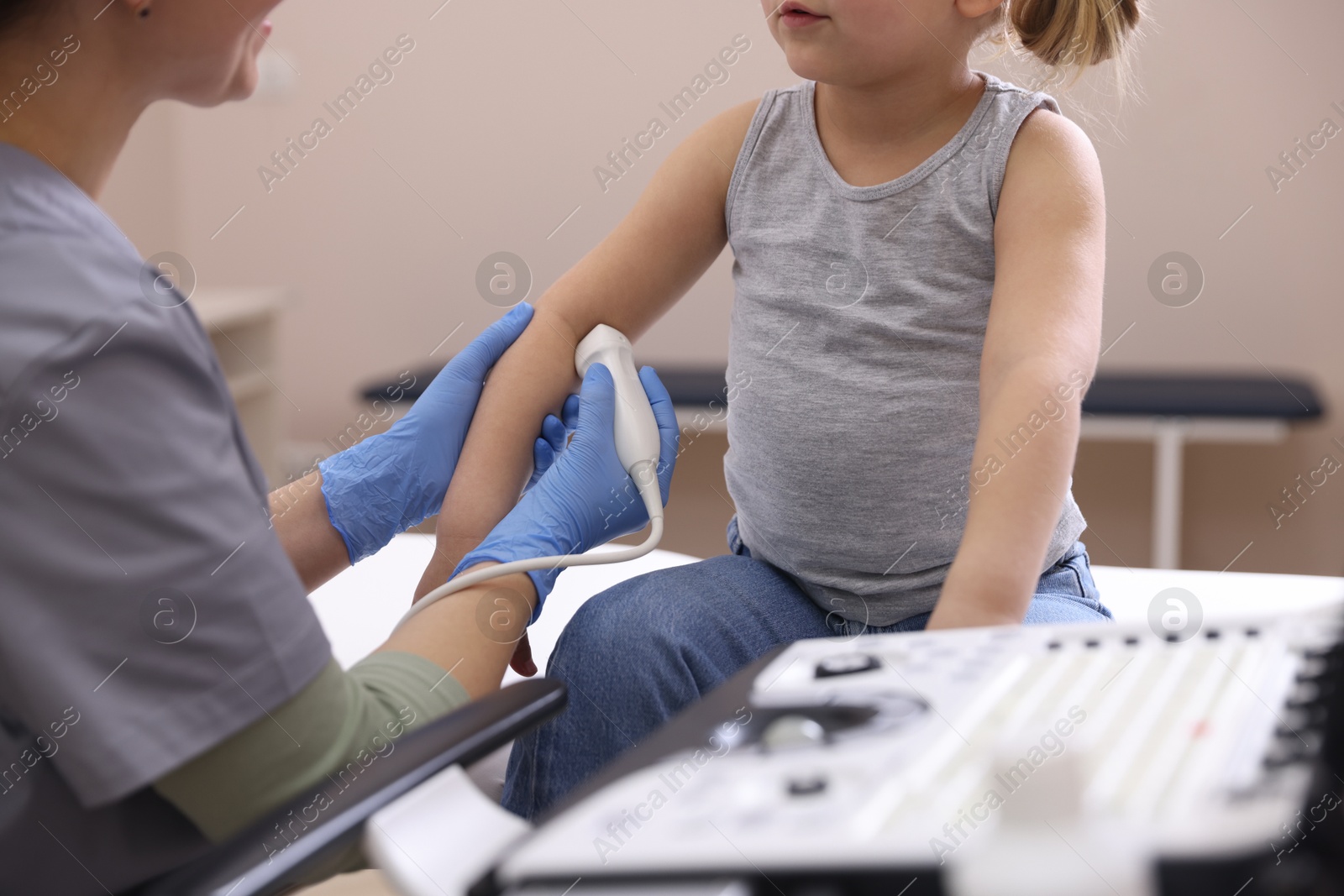 Sonographer conducting ultrasound examination of little girl's arm in clinic, closeup Photo of Sonographer conducting ultrasound examination of little girl's arm in clinic, closeup
