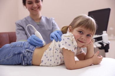 Photo of Sonographer conducting little girl's renal ultrasound examination in clinic, closeup