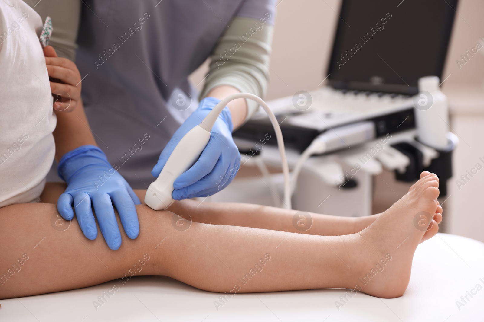 Sonographer conducting ultrasound examination of little girl's knee in clinic, closeup Photo of Sonographer conducting ultrasound examination of little girl's knee in clinic, closeup