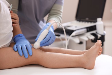 Photo of Sonographer conducting ultrasound examination of little girl's knee in clinic, closeup