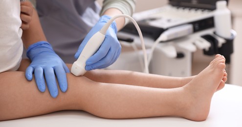 Photo of Sonographer conducting ultrasound examination of little girl's knee in clinic, closeup