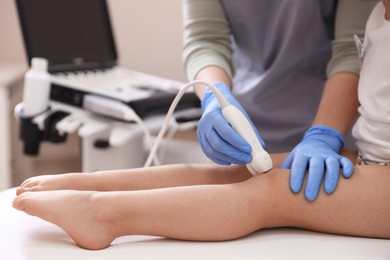Photo of Sonographer conducting ultrasound examination of little girl's knee in clinic, closeup