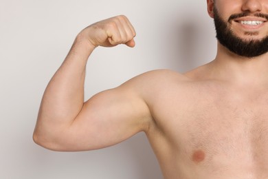 Photo of Man showing his bicep on light background, closeup