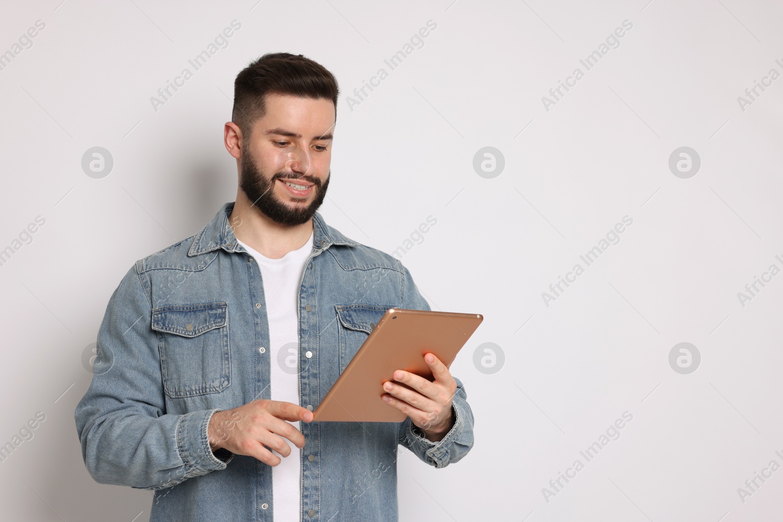 Handsome man using tablet on white background, space for text Photo of Handsome man using tablet on white background, space for text