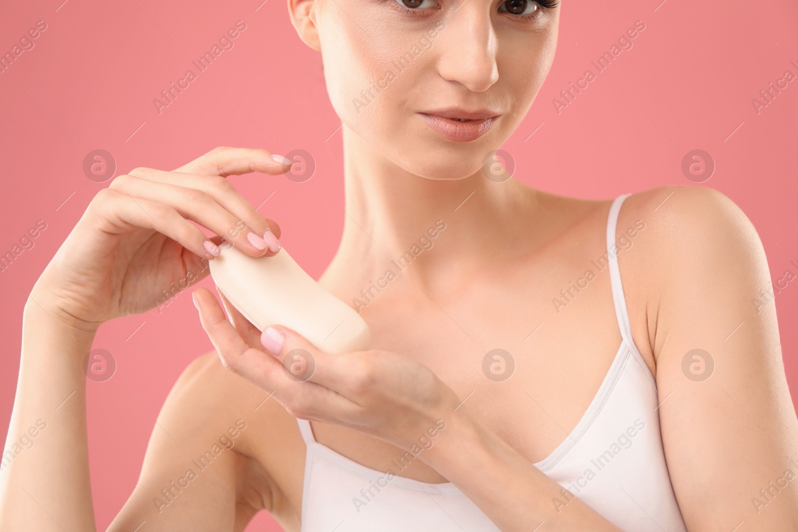 Photo of Beautiful woman with soap bar on pink background, closeup