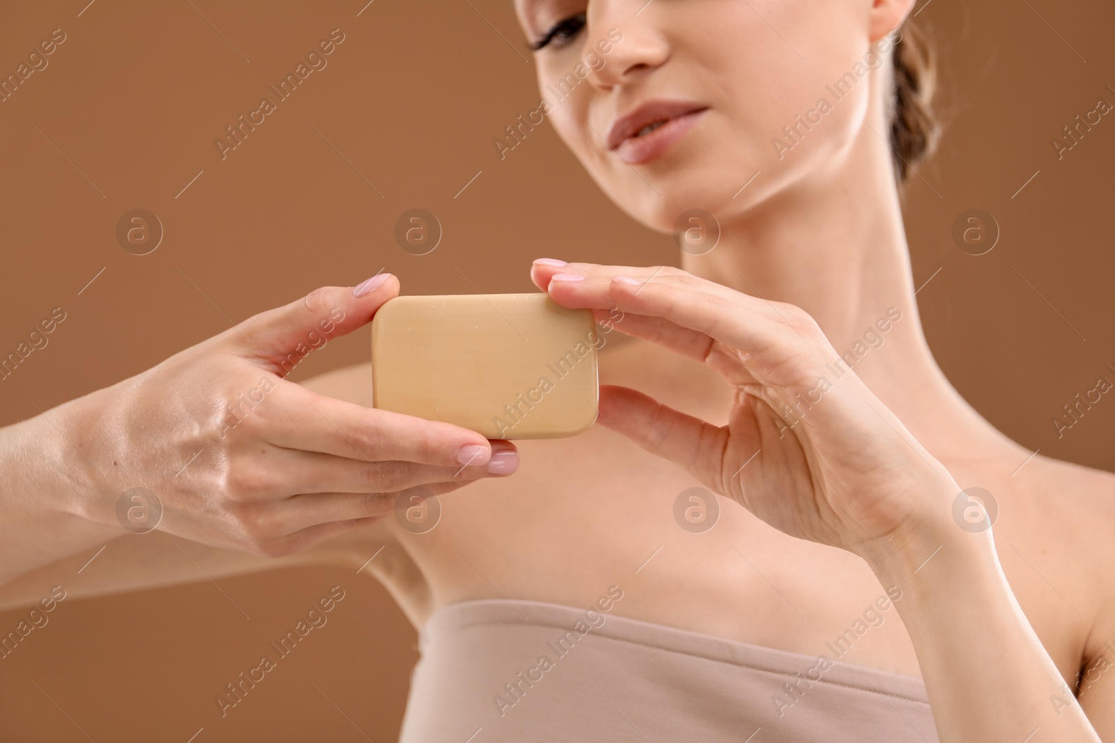 Beautiful woman with soap bar on brown background, closeup Photo of Beautiful woman with soap bar on brown background, closeup