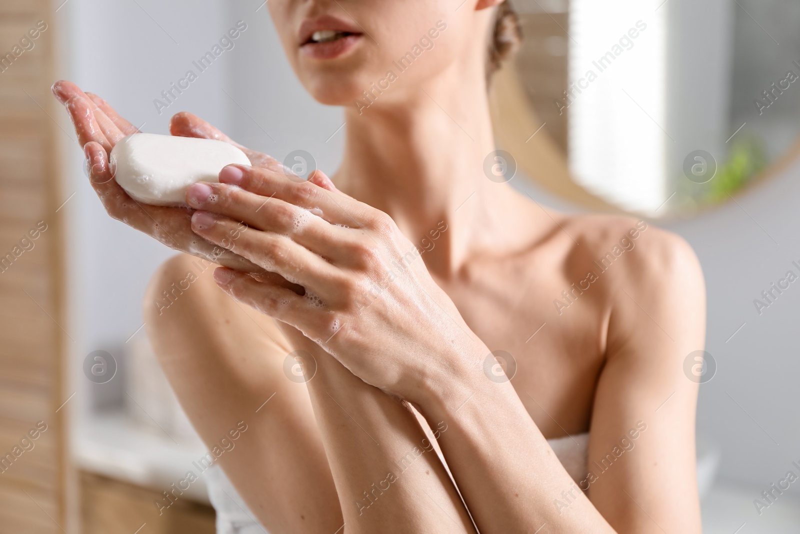 Photo of Woman washing hands with soap bar in bathroom, closeup