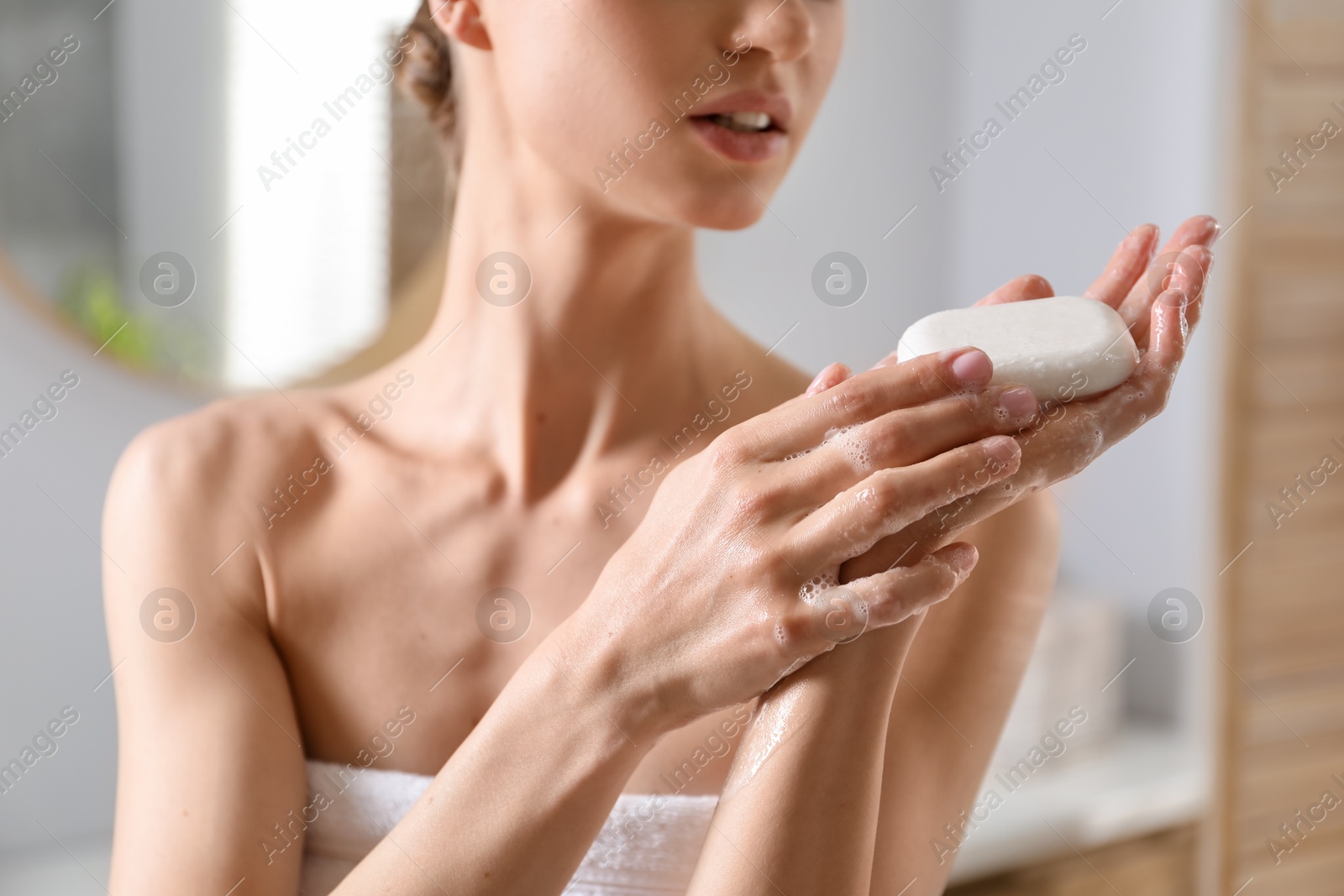 Photo of Woman washing hands with soap bar in bathroom, closeup
