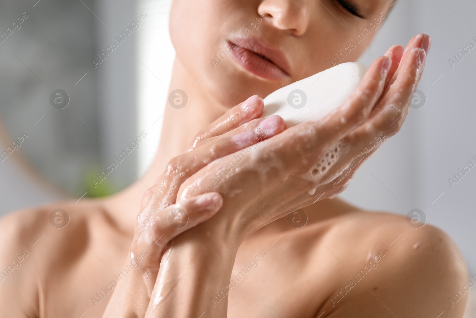 Photo of Woman washing hands with soap bar indoors, closeup