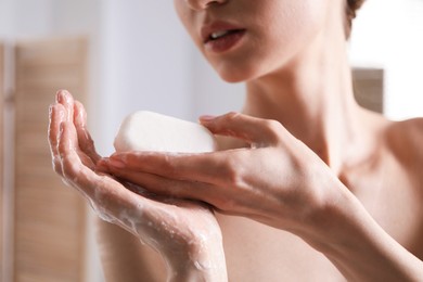 Photo of Woman washing hands with soap bar indoors, closeup