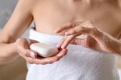Photo of Woman washing hands with soap bar indoors, closeup