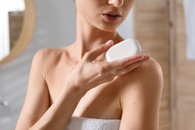 Photo of Woman with soap bar in bathroom, closeup