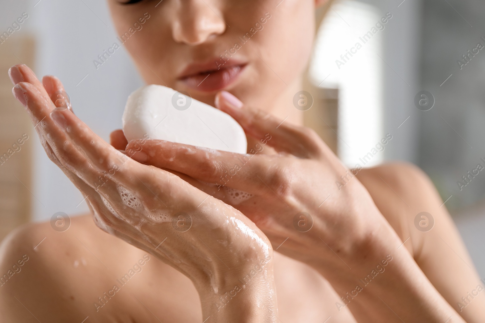 Photo of Woman washing hands with soap bar indoors, closeup