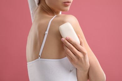 Photo of Woman with soap bar on pink background, closeup