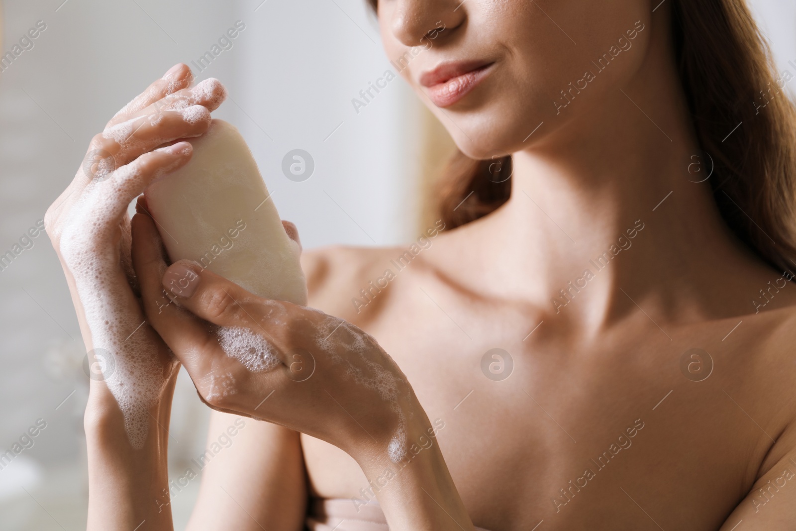 Woman with foaming soap bar indoors, closeup Photo of Woman with foaming soap bar indoors, closeup