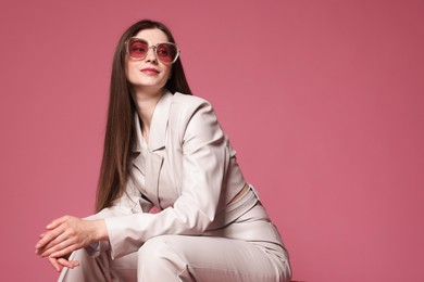Photo of Fashionable portrait of beautiful woman in stylish outfit on pink background. Space for text