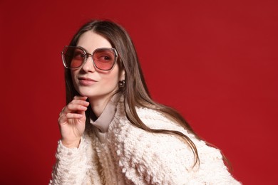 Photo of Fashionable portrait of beautiful woman in stylish outfit on red background