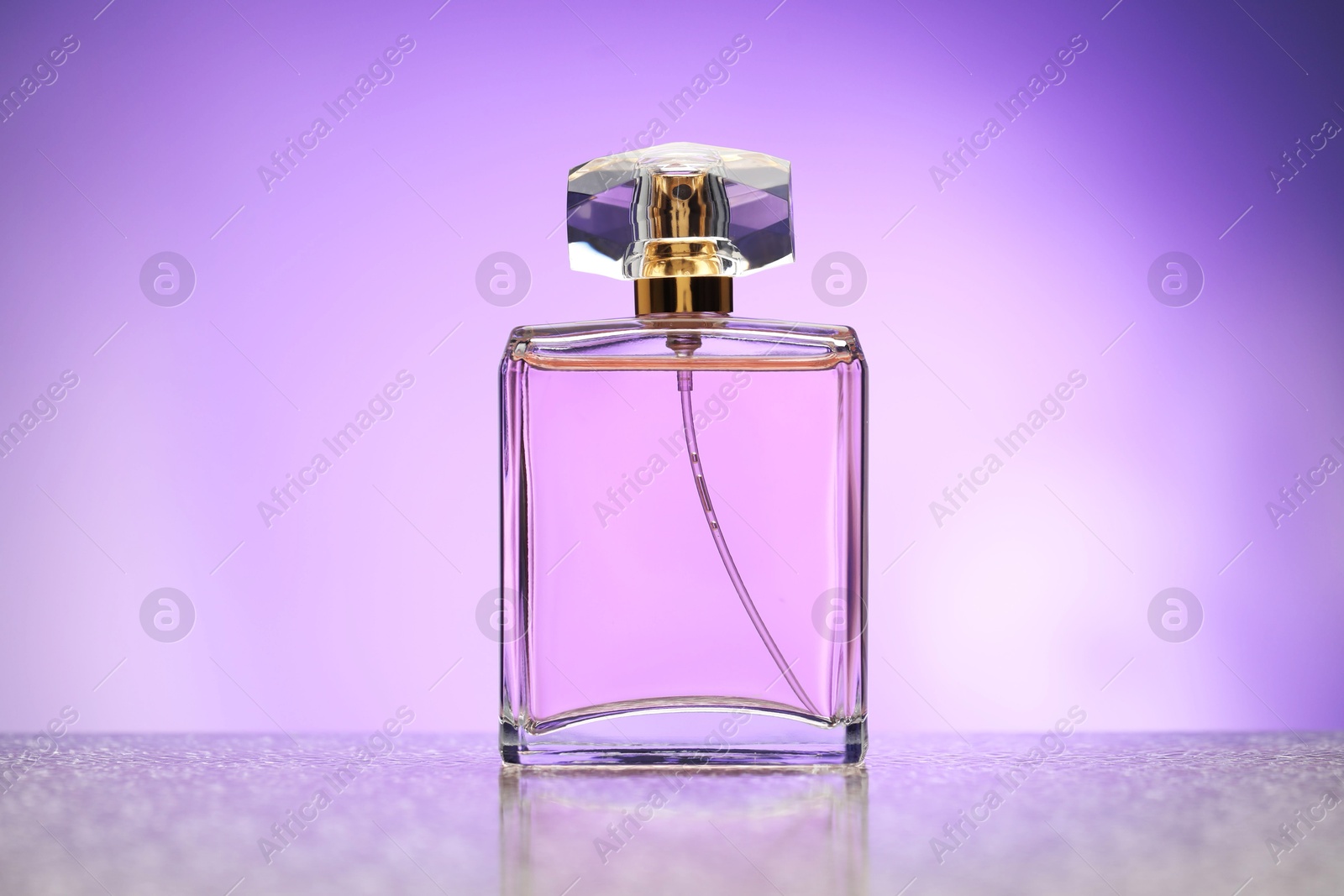 Bottle of perfume on mirror surface against violet gradient background Photo of Bottle of perfume on mirror surface against violet gradient background
