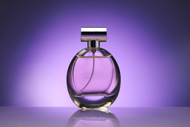 Photo of Bottle of perfume on mirror surface against purple gradient background
