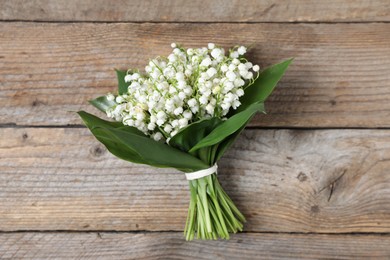 Photo of Bouquet of beautiful lily-of-the-valley flowers on wooden background, top view