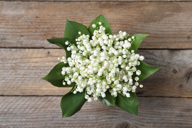 Photo of Bouquet of beautiful lily-of-the-valley flowers on wooden background, top view