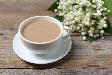 Photo of Bouquet of beautiful lily-of-the-valley flowers and coffee on wooden background, closeup
