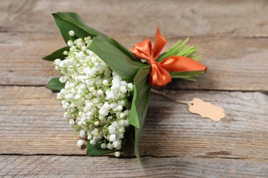 Photo of Bouquet of beautiful lily-of-the-valley flowers on wooden background, closeup
