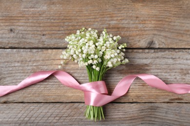 Photo of Bouquet of beautiful lily-of-the-valley flowers on wooden background, top view