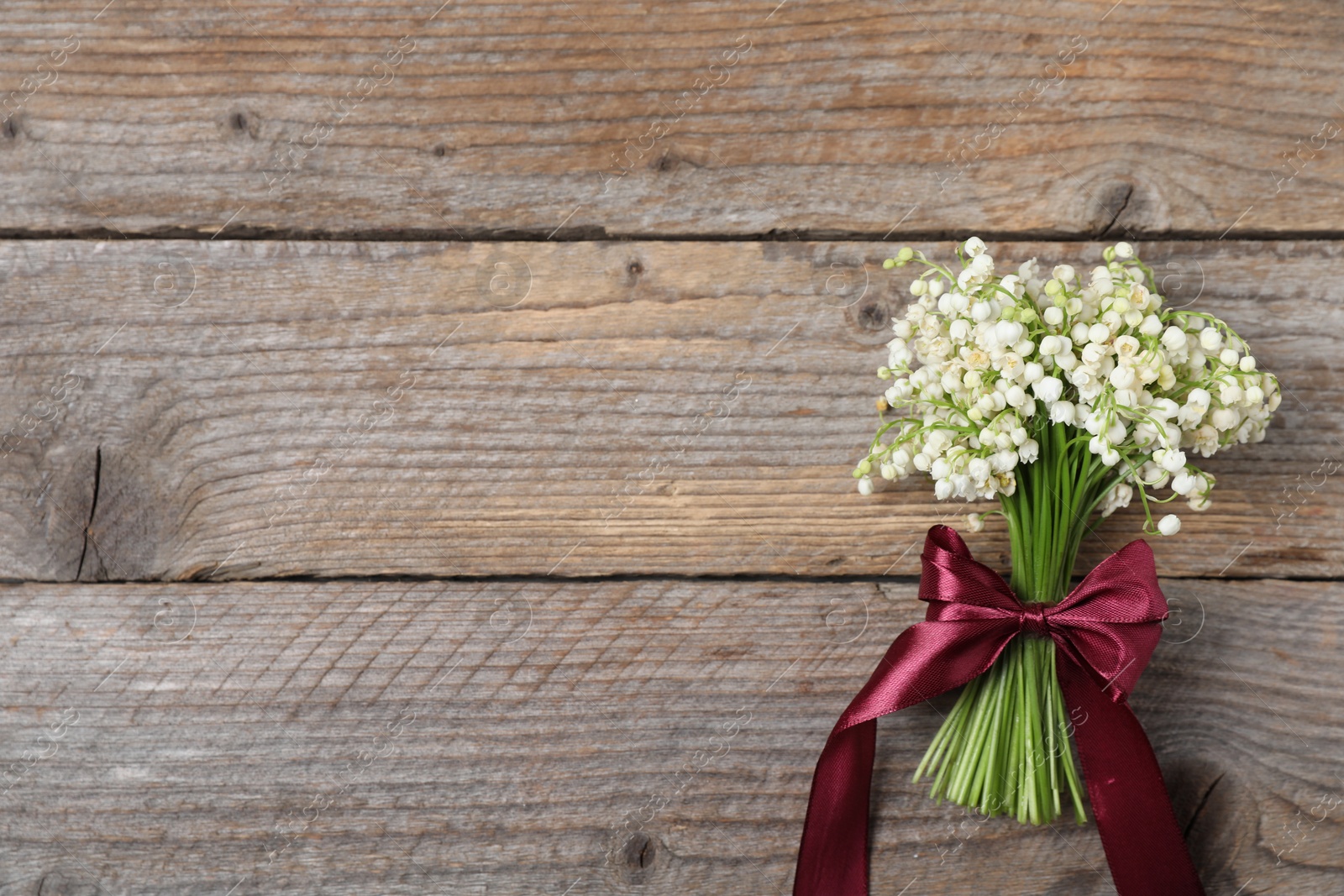 Bouquet of beautiful lily-of-the-valley flowers on wooden background, top view. Space for text Photo of Bouquet of beautiful lily-of-the-valley flowers on wooden background, top view. Space for text