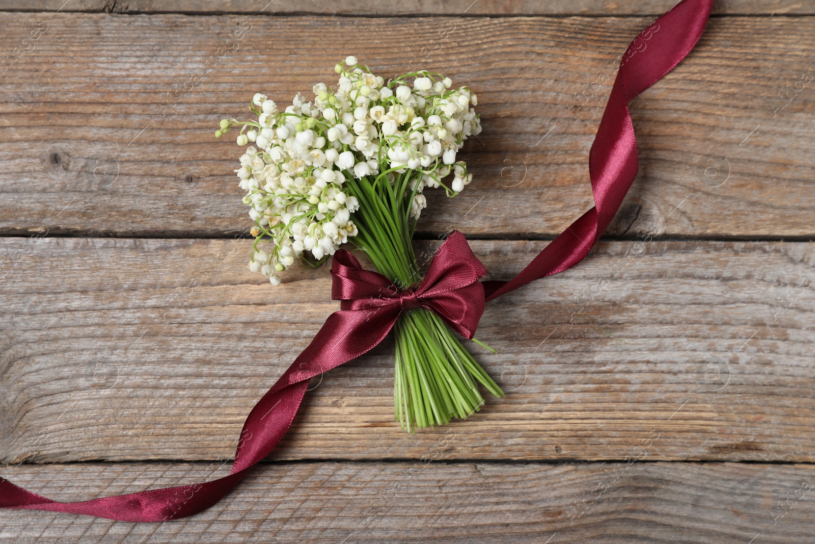 Bouquet of beautiful lily-of-the-valley flowers on wooden background, top view Photo of Bouquet of beautiful lily-of-the-valley flowers on wooden background, top view