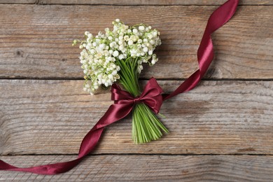 Photo of Bouquet of beautiful lily-of-the-valley flowers on wooden background, top view