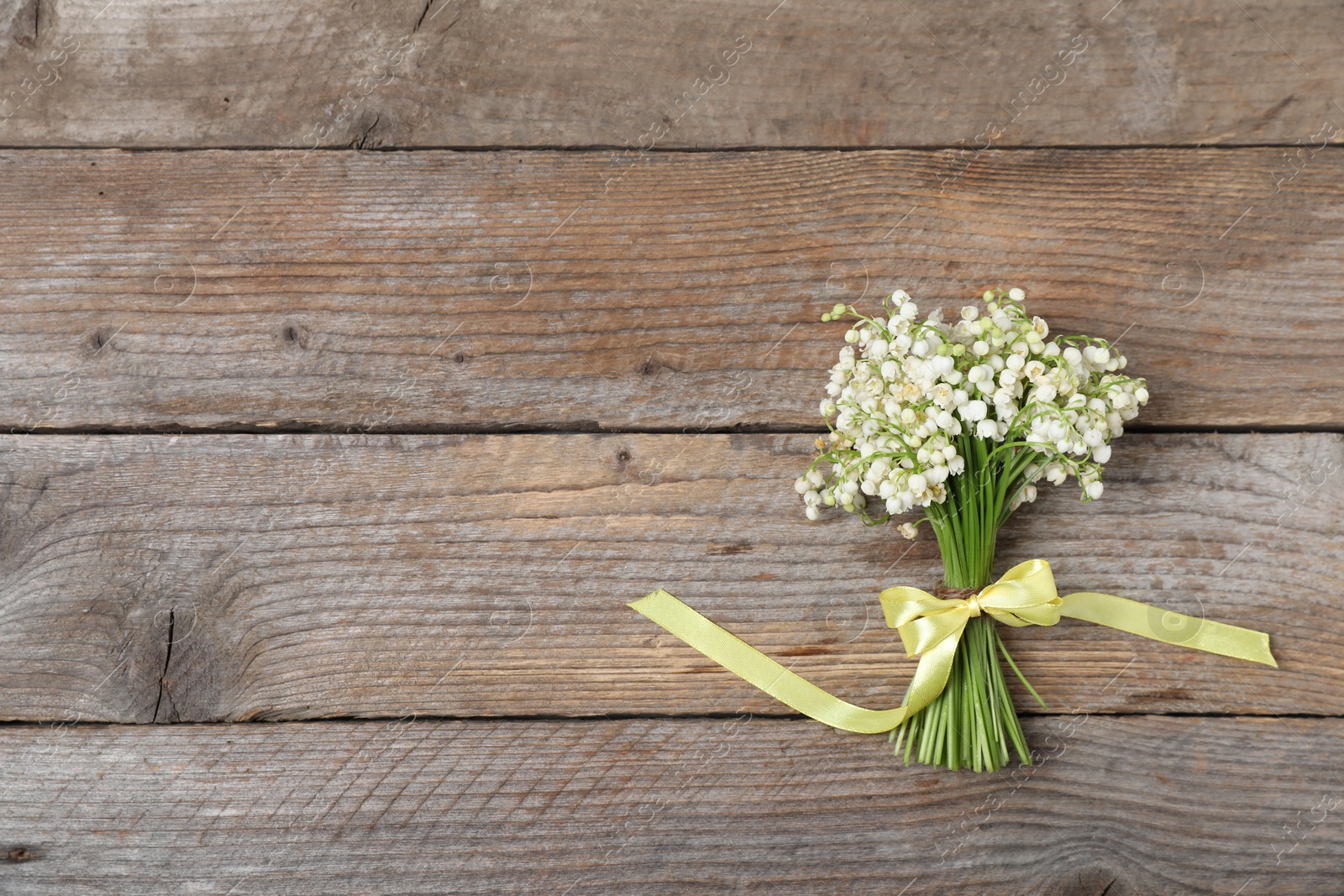 Bouquet of beautiful lily-of-the-valley flowers on wooden background, top view. Space for text Photo of Bouquet of beautiful lily-of-the-valley flowers on wooden background, top view. Space for text