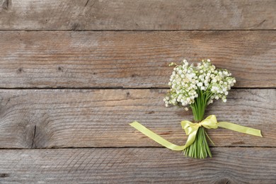Photo of Bouquet of beautiful lily-of-the-valley flowers on wooden background, top view. Space for text