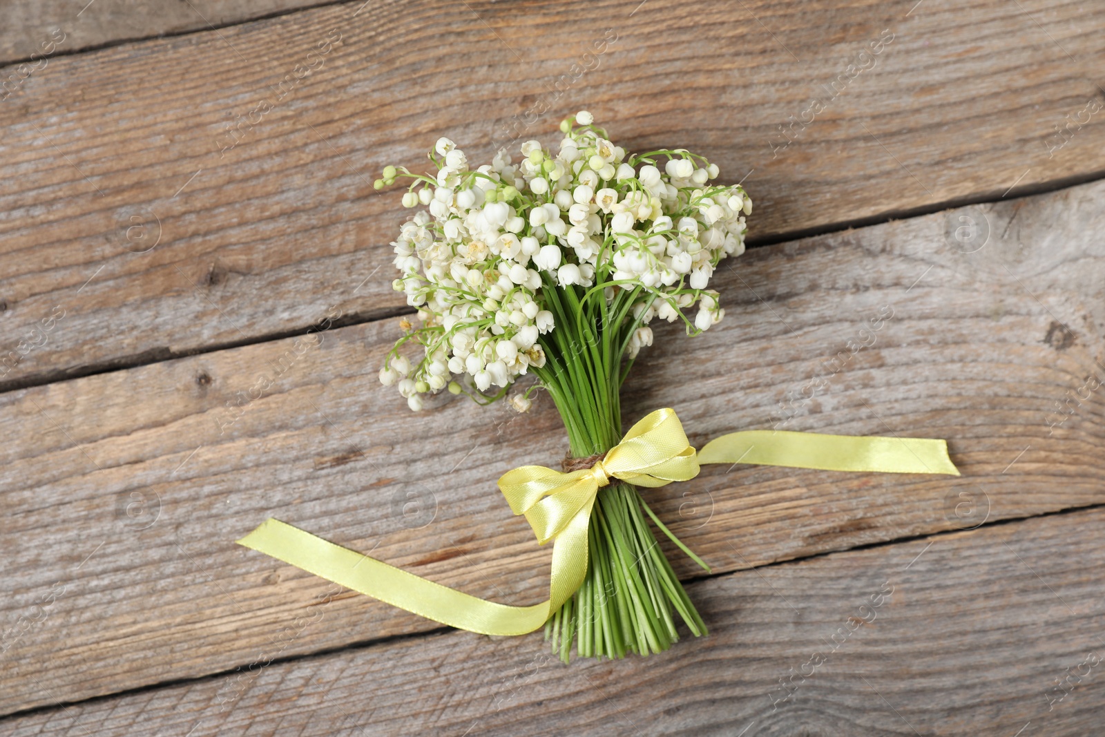 Bouquet of beautiful lily-of-the-valley flowers on wooden background, top view Photo of Bouquet of beautiful lily-of-the-valley flowers on wooden background, top view