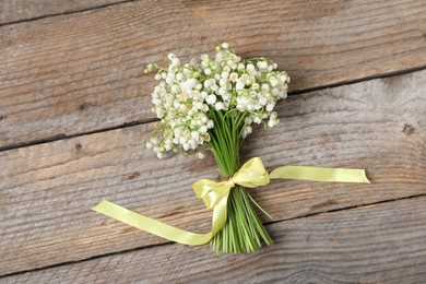 Photo of Bouquet of beautiful lily-of-the-valley flowers on wooden background, top view