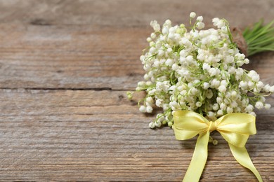 Photo of Bouquet of beautiful lily-of-the-valley flowers on wooden background, closeup. Space for text