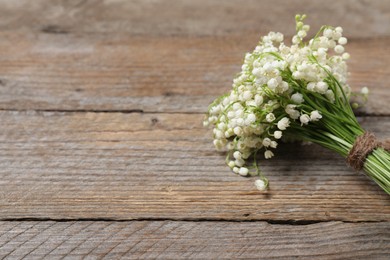 Photo of Bouquet of beautiful lily-of-the-valley flowers on wooden background, closeup. Space for text