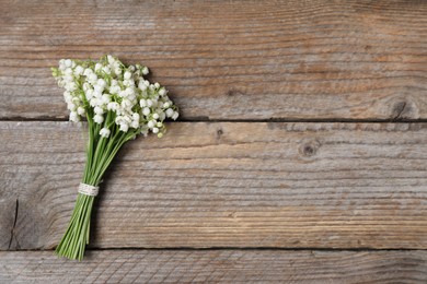 Photo of Bouquet of beautiful lily-of-the-valley flowers on wooden background, top view. Space for text