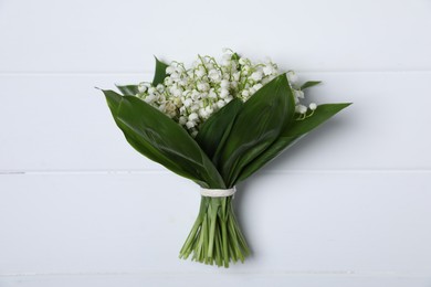Photo of Bouquet of beautiful lily-of-the-valley flowers on white wooden background, top view