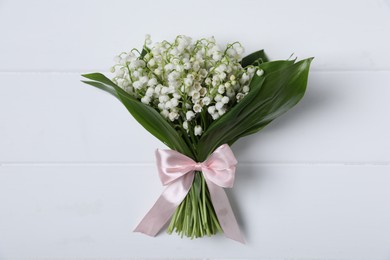 Photo of Bouquet of beautiful lily-of-the-valley flowers on white wooden background, top view