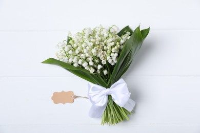 Photo of Bouquet of beautiful lily-of-the-valley flowers on white wooden background, top view