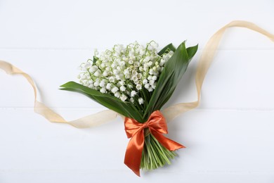 Photo of Bouquet of beautiful lily-of-the-valley flowers on white wooden background, top view