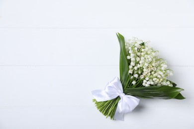 Photo of Bouquet of beautiful lily-of-the-valley flowers on white wooden background, top view. Space for text