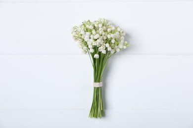 Photo of Bouquet of beautiful lily-of-the-valley flowers on white wooden background, top view